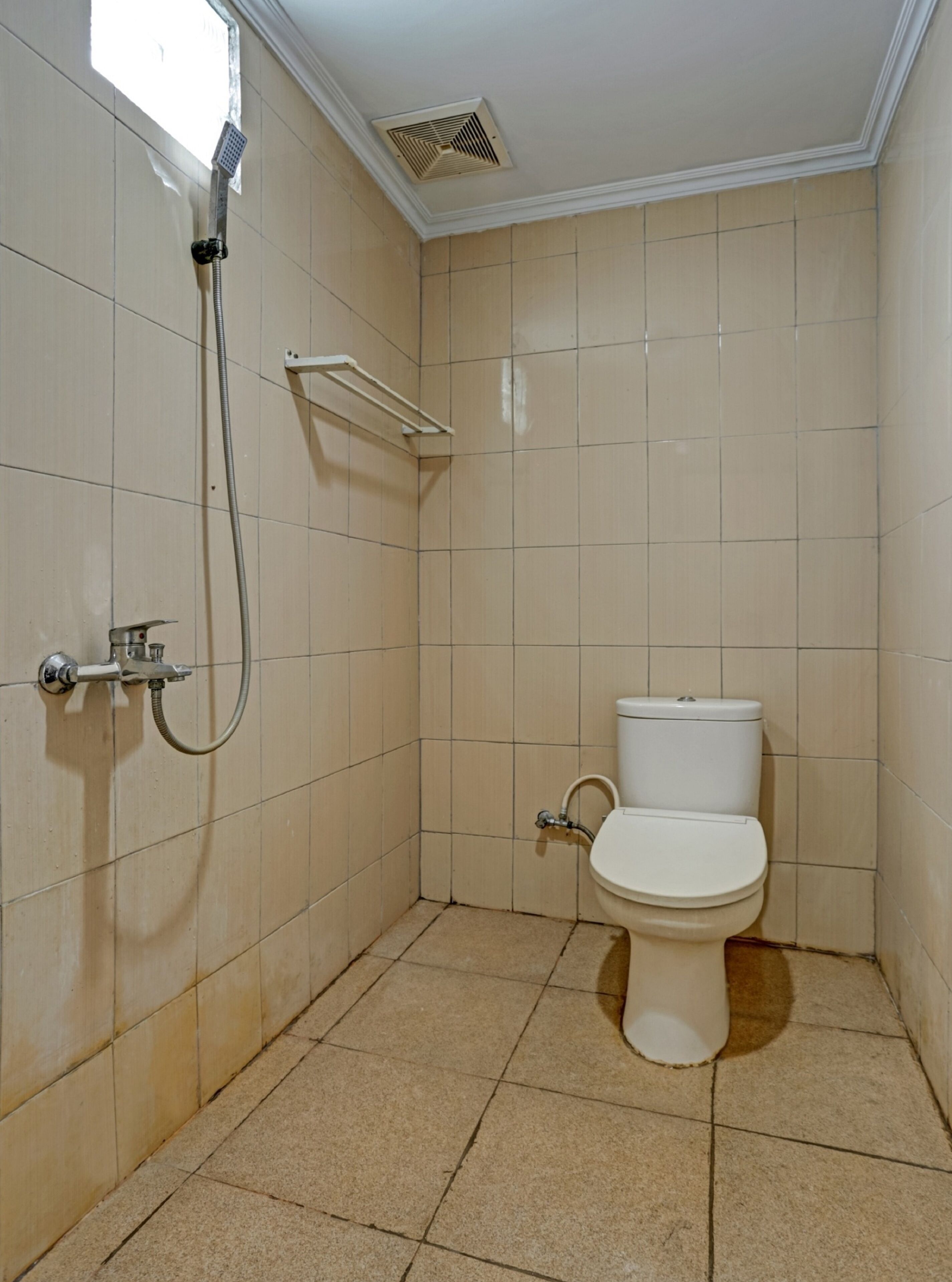 A small bathroom with a toilet, a shower, and a window.