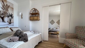 A hotel room with a bed, a chair, a small table, and a door leading to another room. - Panoramic sea view of port and beaches (Bandol)