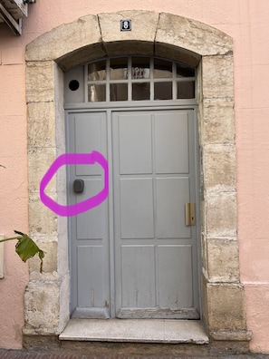 Eine graue Tür mit Messingbeschlägen, ein steinernes Portal und ein Schild mit der Nummer 8 darüber.
