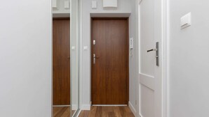 Un couloir avec des portes en bois et des murs blancs.