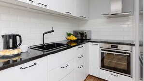 Une cuisine moderne avec des armoires blanches, un plan de travail noir, un four en acier inoxydable et un robinet noir.