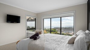 Un dormitorio con una cama grande, un televisor de pantalla plana y un balcón con vistas.