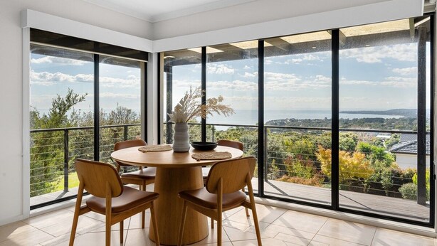 Un comedor con una mesa redonda y sillas, ventanas amplias con vistas al paisaje.