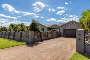A residential house with a paved driveway, a garage, and a decorative fence.