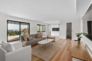 A modern living room with a sofa, coffee table, and a view of a balcony.