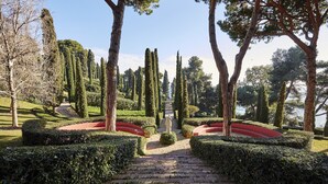 A formal garden with a central statue, neatly trimmed hedges, and a stone pathway leading to a body of water. - Apt, 4 pax LLoret de Mar - Fenals - wifi, community pool a few meters from the beach. Vivalidays Elia. (Lloret de Mar)