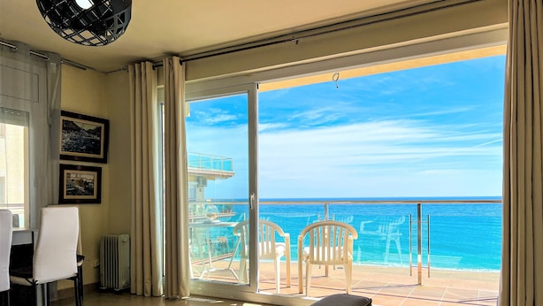 A hotel room with a large sliding glass door leading to a balcony with a view of the ocean. - Apartment 4/5 Pax with direct access to the beach. It has a community pool. Excellent location, bars, restaurants, shops and promenade. Free WIFI. Vivalidays Mar. (Santa Susana)