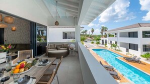 A modern outdoor dining area with a pool, lounge chairs, and a view of the pool. - Penthouse Mesa Bonita – Modern Caribbean Luxury (Jan Thiel)