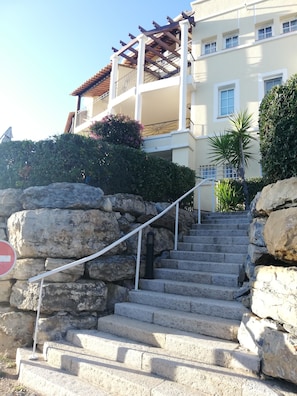 A building with a stone staircase leading to a balcony with a pergola.