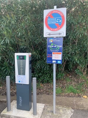 Eine Ladestation für Elektrofahrzeuge mit Schild, das reservierte Parkplätze für Elektroautos kennzeichnet.
