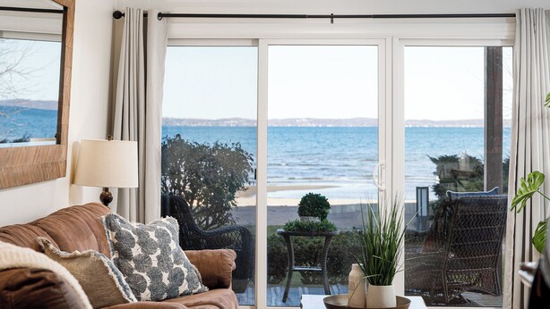 Un salon avec vue sur la mer, un canapé, une table avec une plante et un fauteuil.