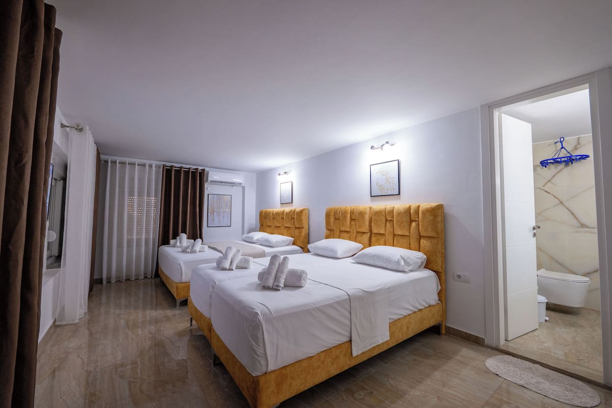 Habitación de hotel con dos camas, baño y vistas al exterior.