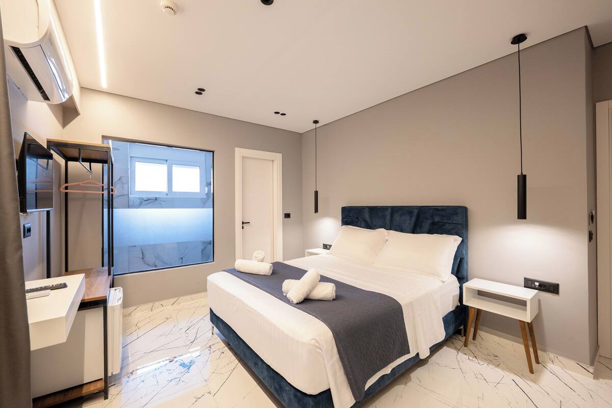 Un dormitorio moderno con una cama grande, mesitas de noche, un armario y una ventana con vistas.
