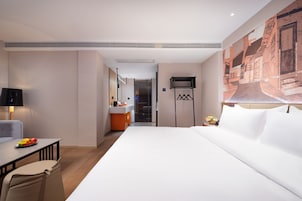 Ein Hotelzimmer mit einem Bett, einem Schreibtisch, einem Sessel, einem Fernseher und einem Bild an der Wand.