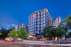 Un hotel moderno con un logo 'K' ben visibile, diversi piani e una facciata luminosa.