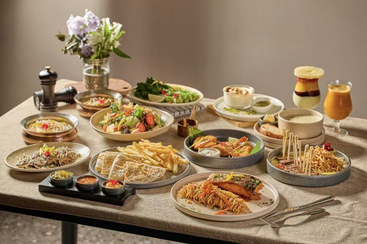 A table with various dishes, including pasta, salads, and desserts, suggesting a dining experience.