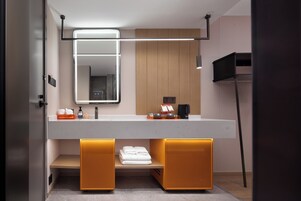 Un bagno moderno con uno specchio grande, un porta asciugamani e un piano di lavoro con articoli da toilette.