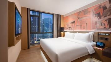 Un hotel moderno con una cama grande, vistas a la ciudad, un panel de control digital y un televisor montado en la pared.