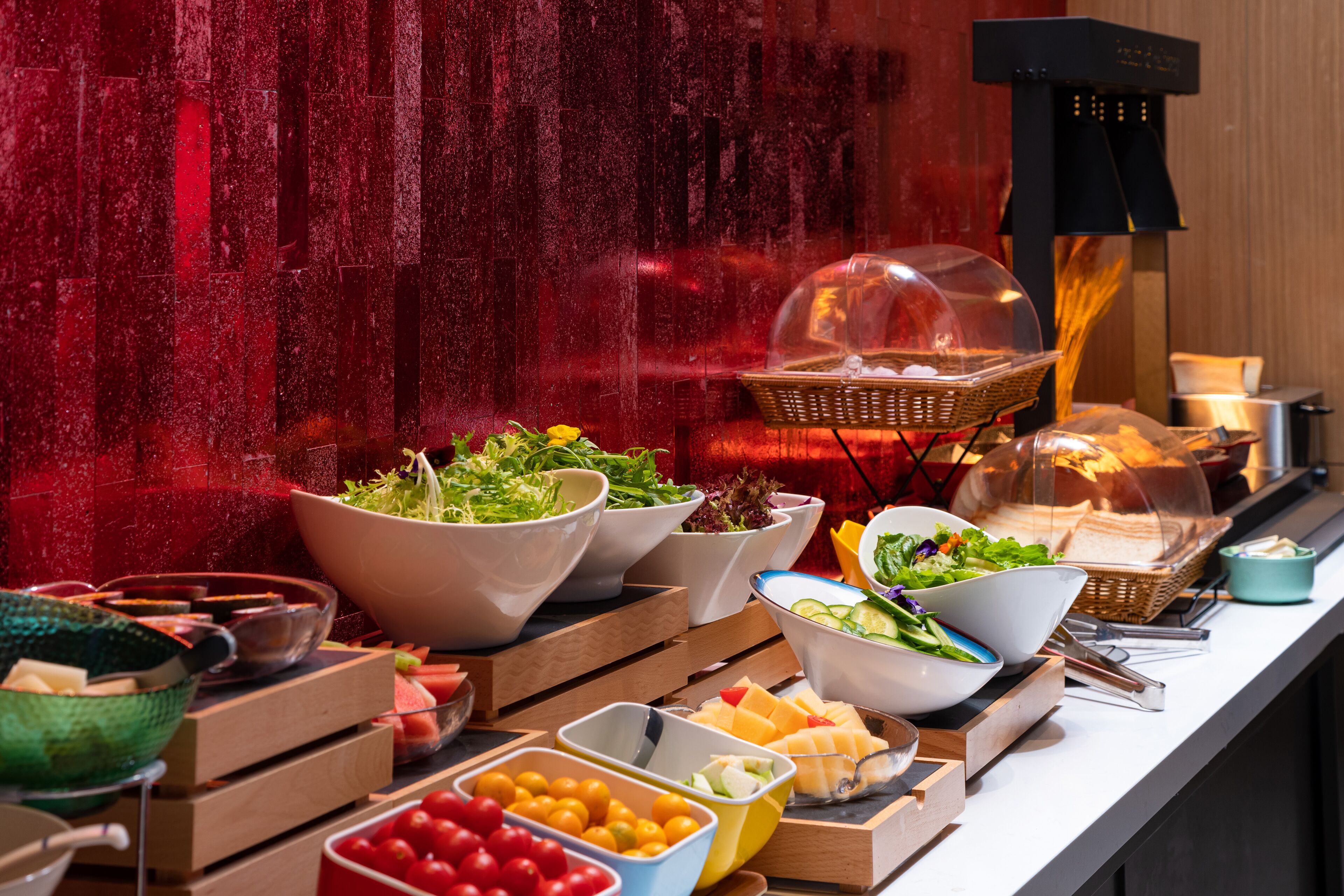 A buffet with various food items and a decorative wall.