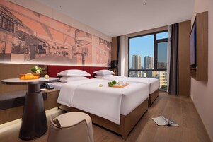 Camera d'albergo con un letto grande, una scrivania, una sedia, un tavolo e vista sulla città.