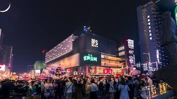 Una bulliciosa calle urbana nocturna con edificios iluminados y una multitud de gente.