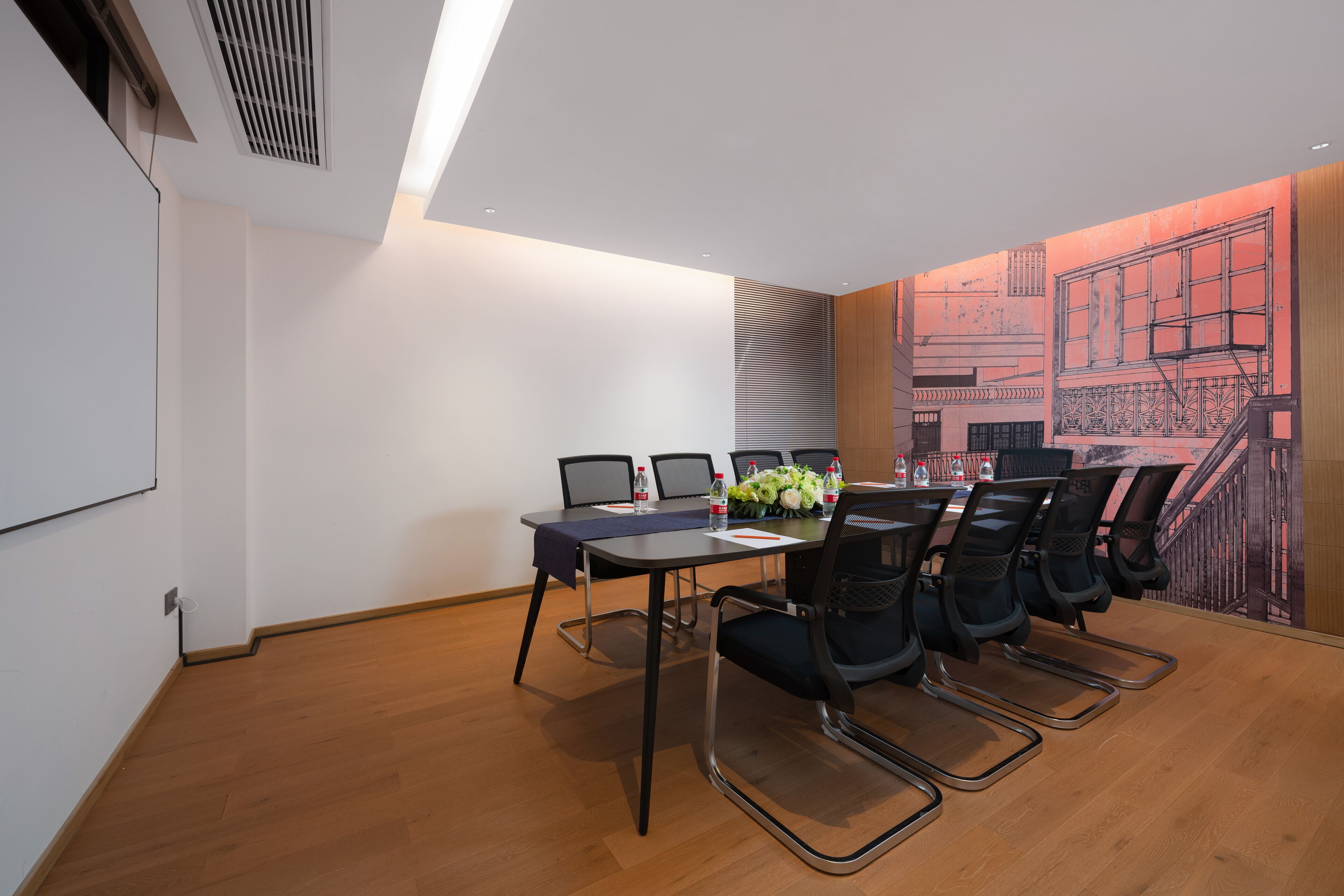 A conference room with a long table, chairs, and a projector screen.