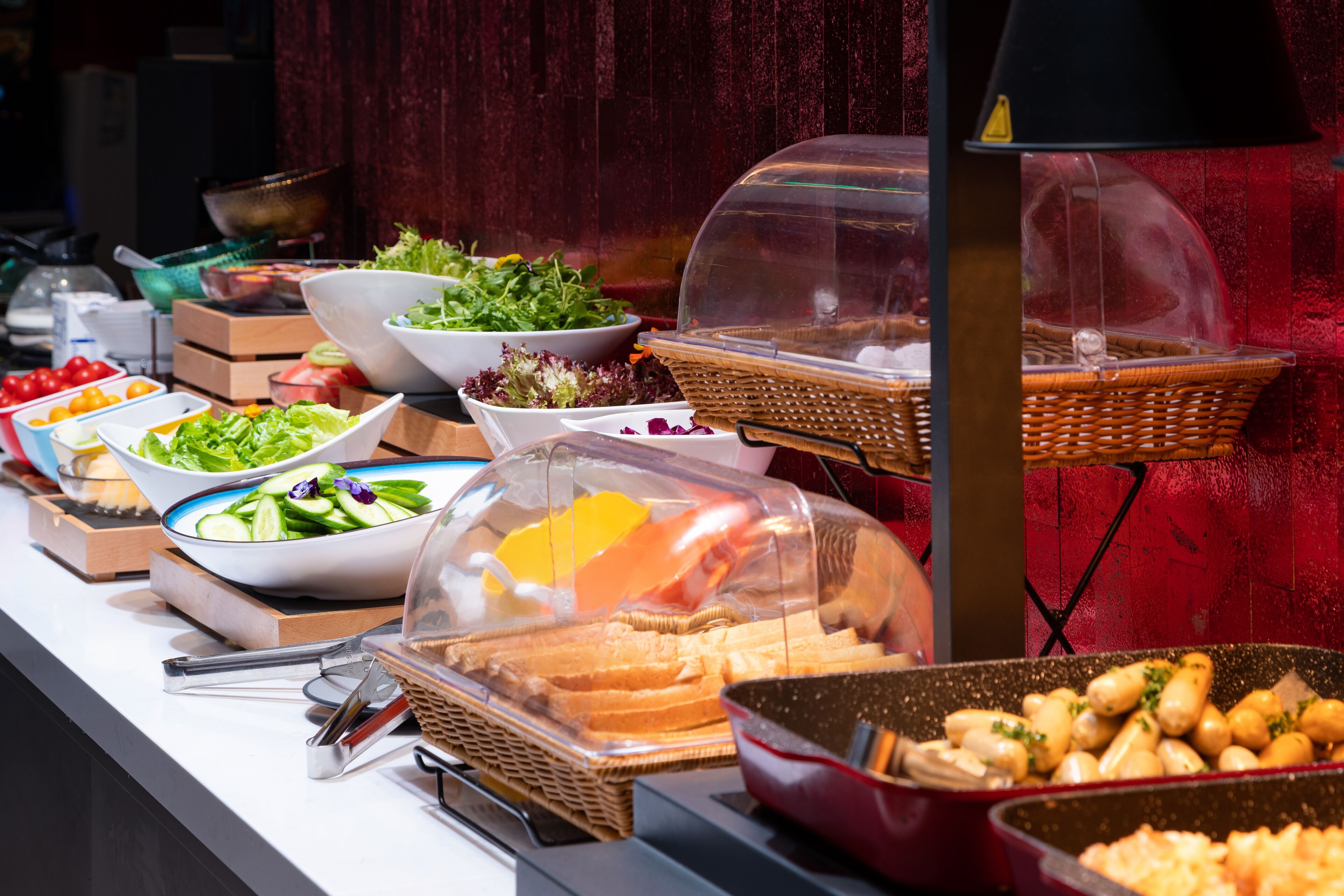 Ein reichhaltiges Buffet mit verschiedenen Speisen, darunter Salate, Früchte und Brot, präsentiert in Körben und Schalen.