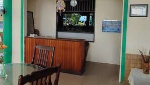 Un espace d’accueil avec un bureau en bois, des chaises, une table en verre et une vue par la fenêtre.