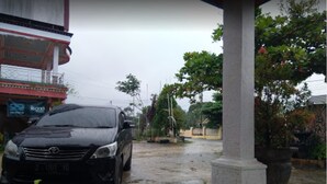 Une voiture noire est garée devant un bâtiment sur lequel on peut lire l’inscription « Eco ».