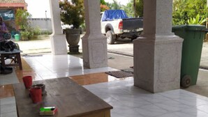 Un espace extérieur abrité, avec une table et des chaises, une poubelle et un camion garé.