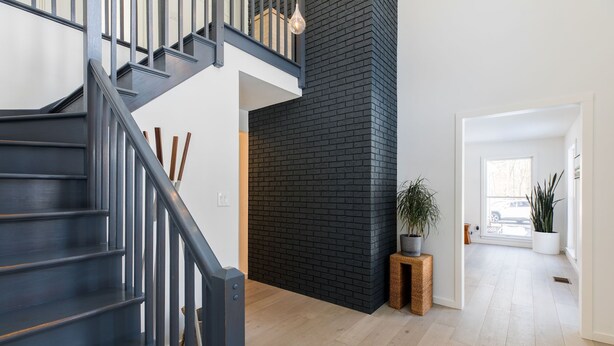 A modern interior with a staircase, a black brick wall, and a wooden floor. - Green Sanctuary: Luxury Home Surrounded by Nature (New Paltz)