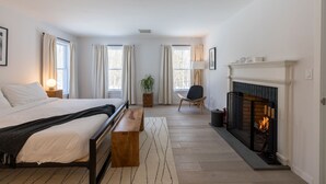 A bedroom with a bed, bedside table, bench, fireplace, and windows. - Green Sanctuary: Luxury Home Surrounded by Nature (New Paltz)