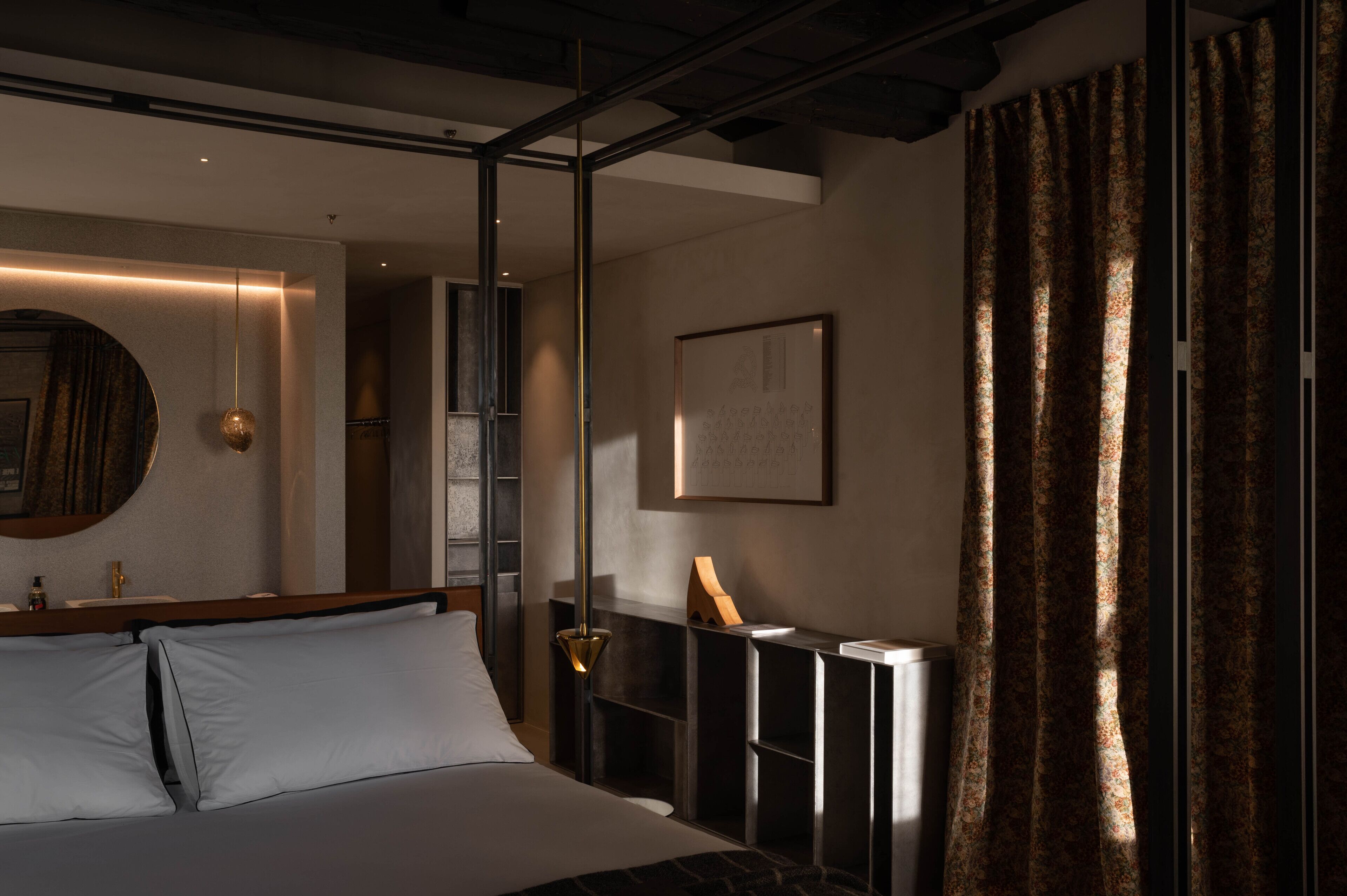 Una habitación de hotel moderna con una cama, una mesita de noche, un espejo y una ventana con cortinas.