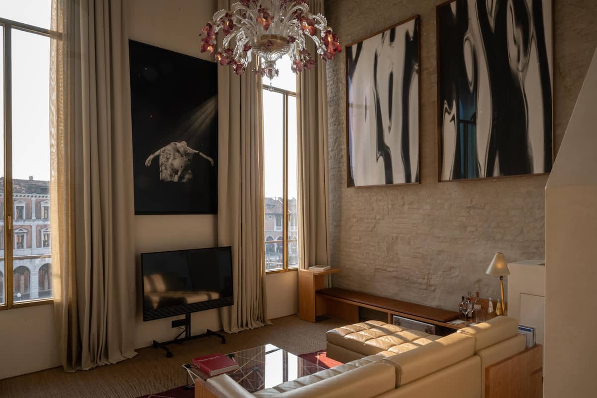 Een moderne woonkamer met een groot raam, een flatscreen televisie, een bank en abstracte kunst aan de muren.