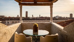 A terrace with a glass table and chairs, overlooking a cityscape with historic buildings and a tower. - The Venice Venice Hotel (Venice)