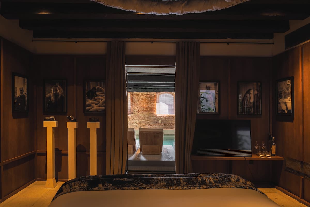 Een slaapkamer met een groot bed, een televisie en uitzicht op een buitenmuur en raam.