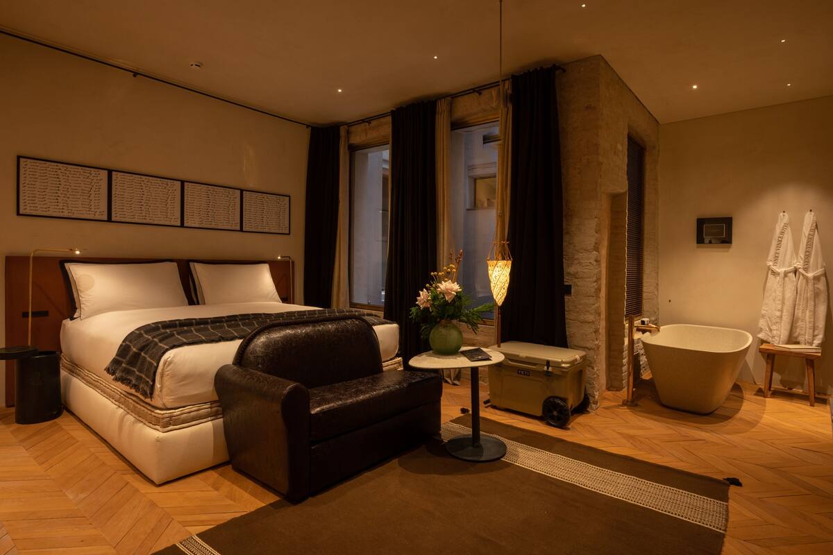 Een moderne slaapkamer met een groot bed, een zithoek, een kaptafel en een badkuip.