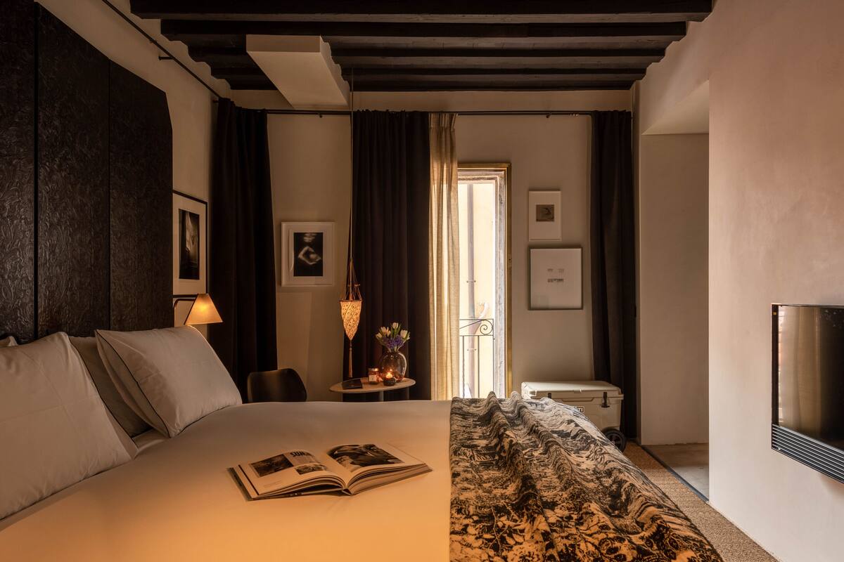 Een hotelkamer met een bed, een televisie, een bureau met een lamp en uitzicht op buiten.