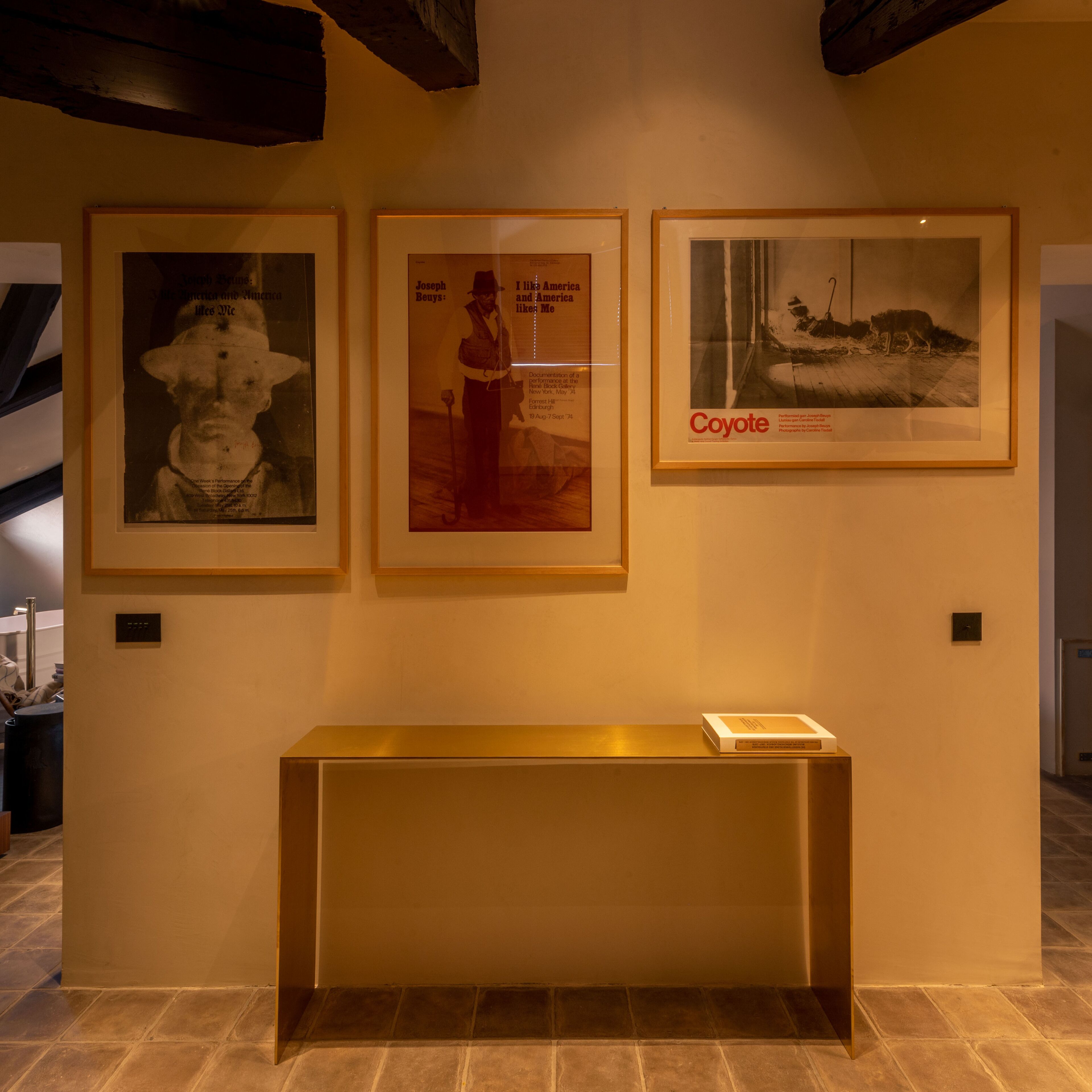 Een galerijwand met ingelijste kunstwerken en een centraal presentatietafeltje.