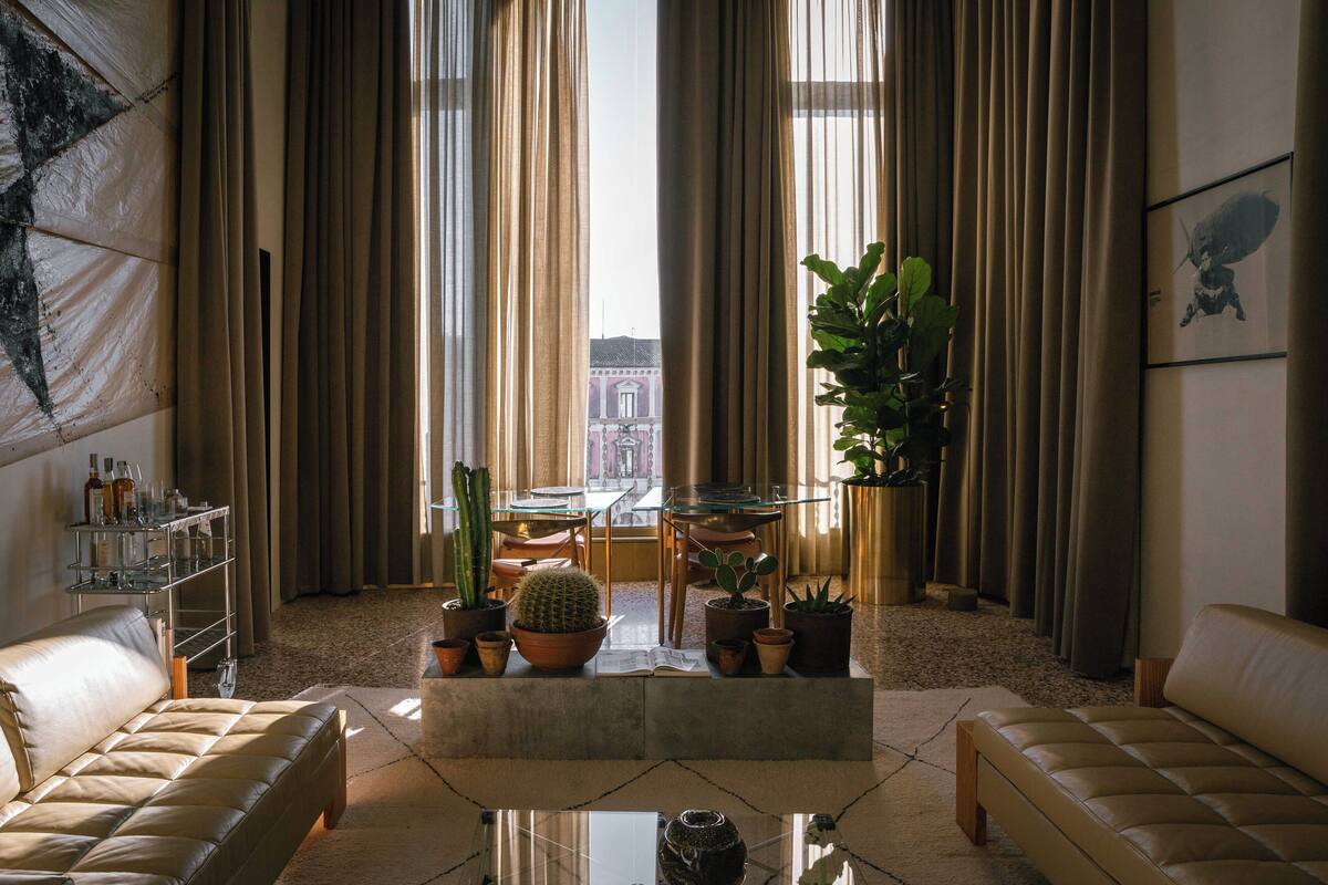 Een moderne woonkamer met een leren bank, een glazen salontafel en diverse potplanten.