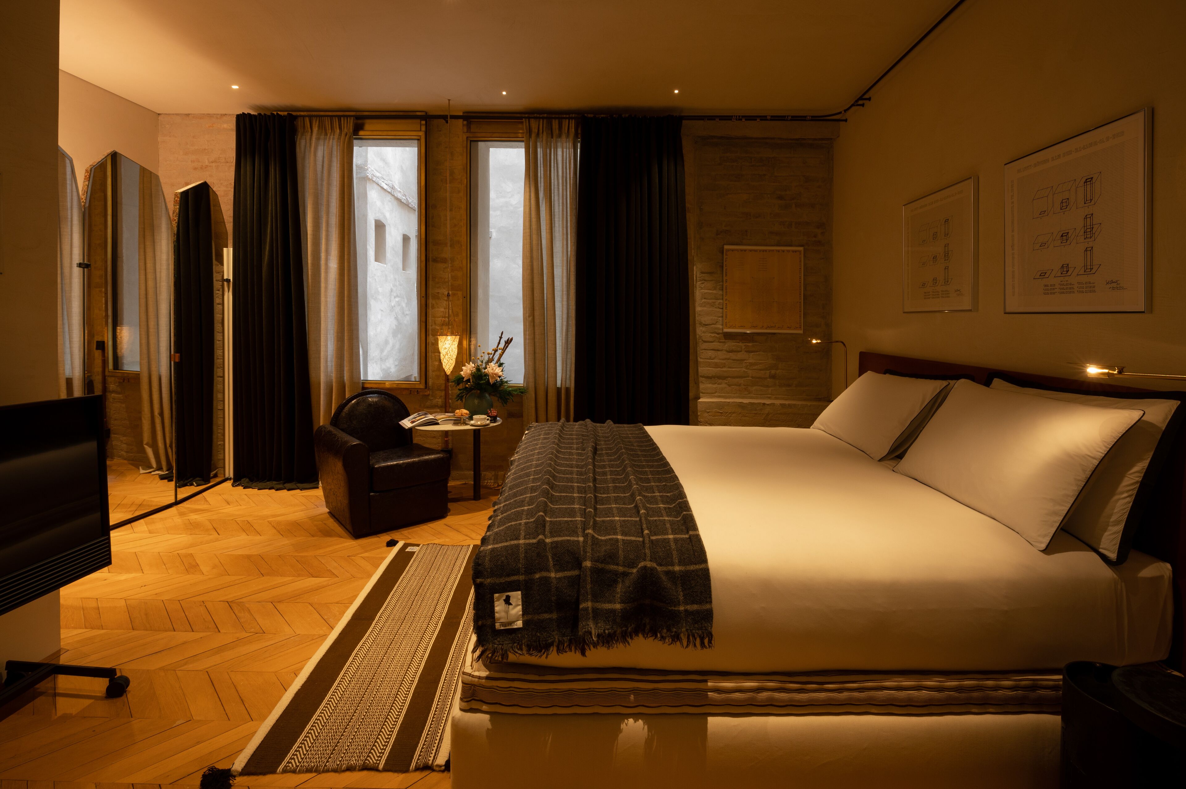 A hotel room with a large bed, a TV, a desk, and a chair.