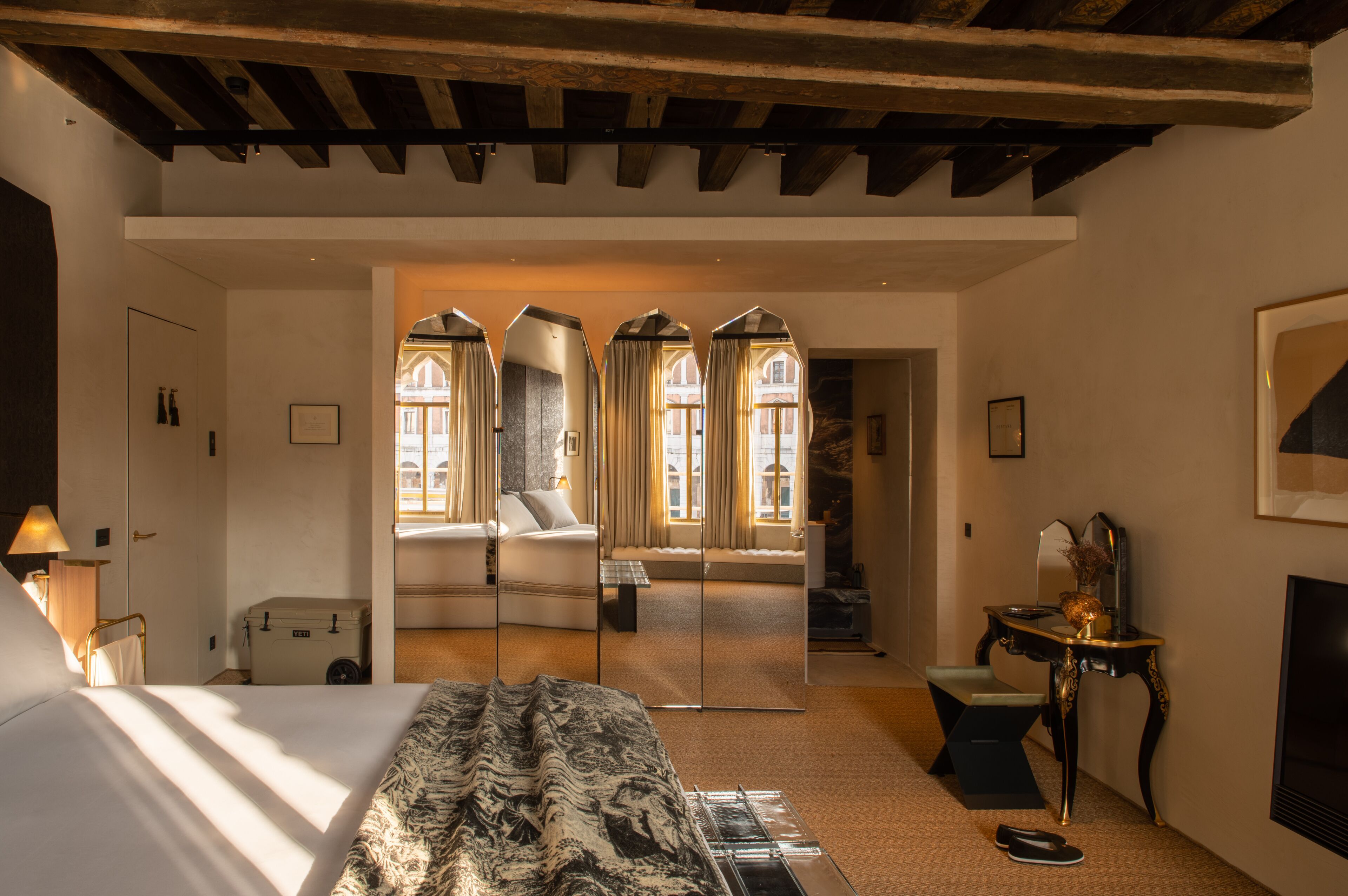 Una camera d'albergo con un letto grande, una scrivania, una sedia, uno specchio e un camino.