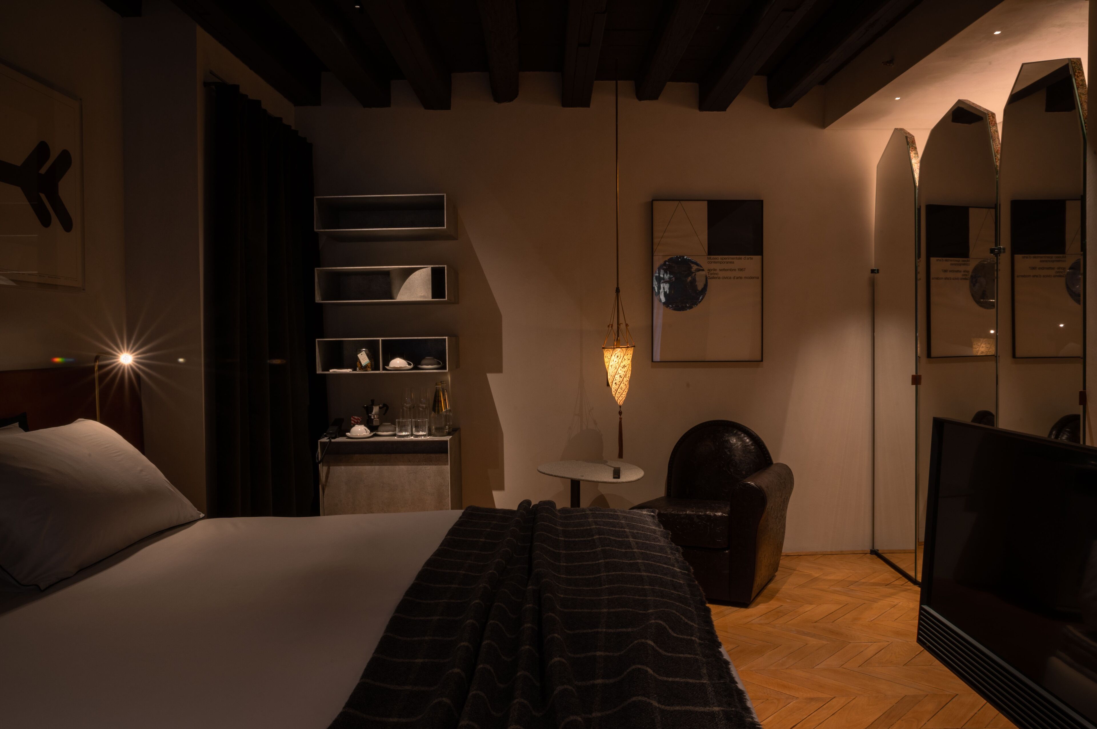Une chambre d’hôtel avec un lit, un bureau avec une lampe, une chaise, une télévision et un miroir.