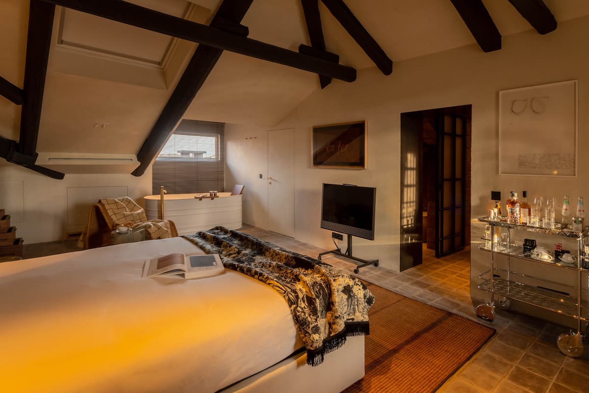 Een slaapkamer met een groot bed, een televisie, een bureau en een minibar.