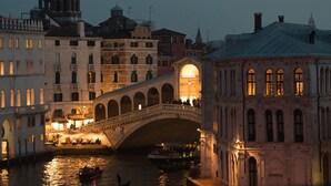 A historic bridge with arches, a river, and buildings with illuminated windows. - The Venice Venice Hotel (Venice)