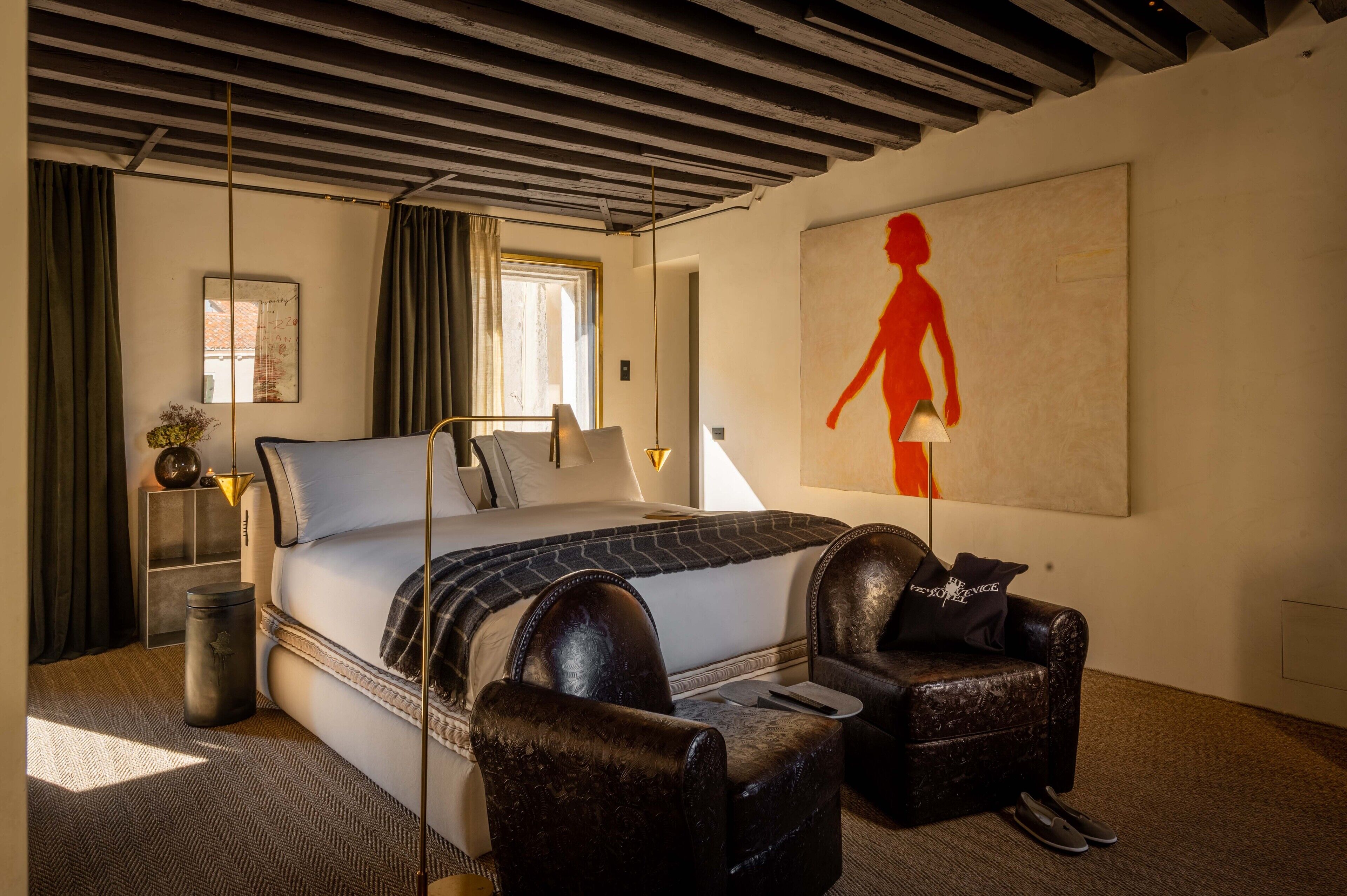 Un dormitorio moderno con una cama grande, una silla, una lámpara y un cuadro en la pared.