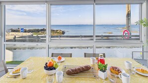 Een eettafel met eten en drinken, een uitzicht op zee, en een verbodsbord voor parkeren.