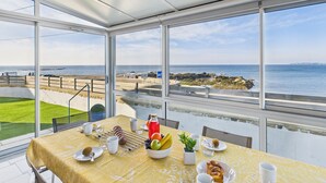 Een tafel gedekt met ontbijtartikelen, met uitzicht op zee, en een logo van Mariette Immobiliere.