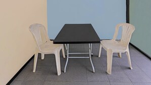 A small room with a black table and two white plastic chairs. - Hotel O Penginapan ReniNearMall Nagoya Hill (Batam)