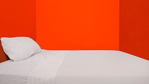 A bed with white bedding in a room with orange walls. - Hotel O Penginapan ReniNearMall Nagoya Hill (Batam)